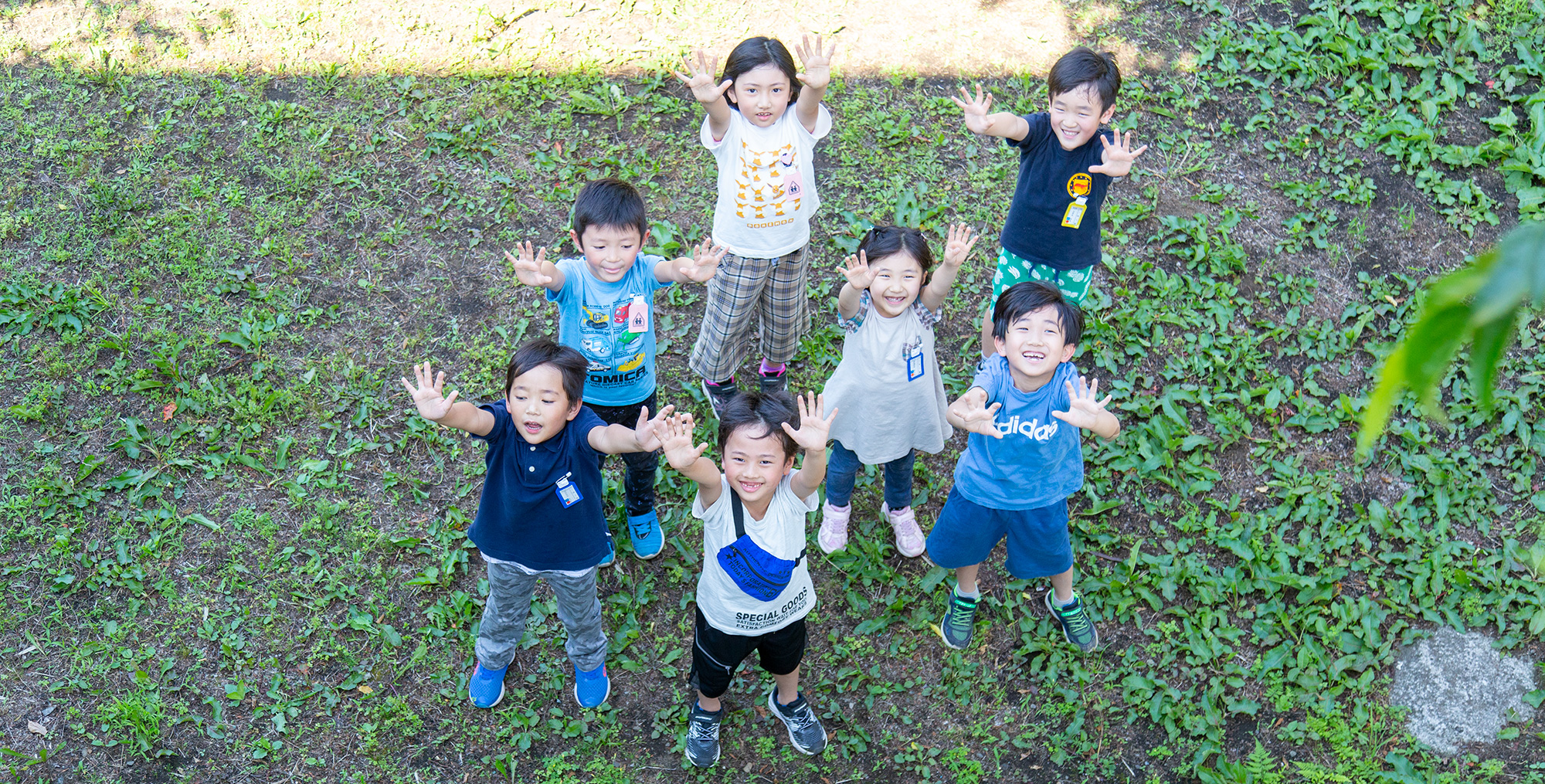 外で笑顔で手を挙げる子どもたち７名